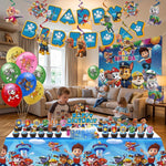 Une fête d'anniversaire réaliste sur le thème de la Pat' Patrouille dans un salon de maison. Deux jeunes garçons sont assis devant une table de desserts remplie d'un gâteau 'Happy Birthday' et de cupcakes décorés de figurines de personnages (Chase, Marshall, Skye, etc.). Le salon est décoré de ballons, de bannières et de serpentins de la Pat' Patrouille.