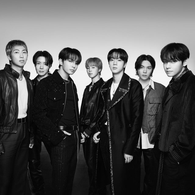 Portrait en noir et blanc des sept chanteurs du groupe BTS, habillés avec des vestes sombres, du cuir et des tenues chics.